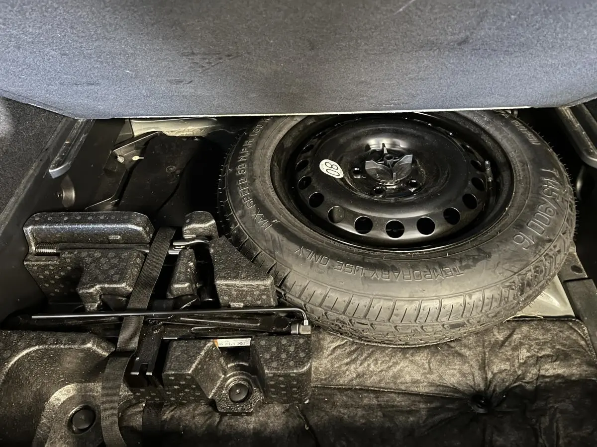 Roue de secours galette noire et outils de bord dans le coffre du Renault Arkana 1.6 E-Tech Hybride noir.