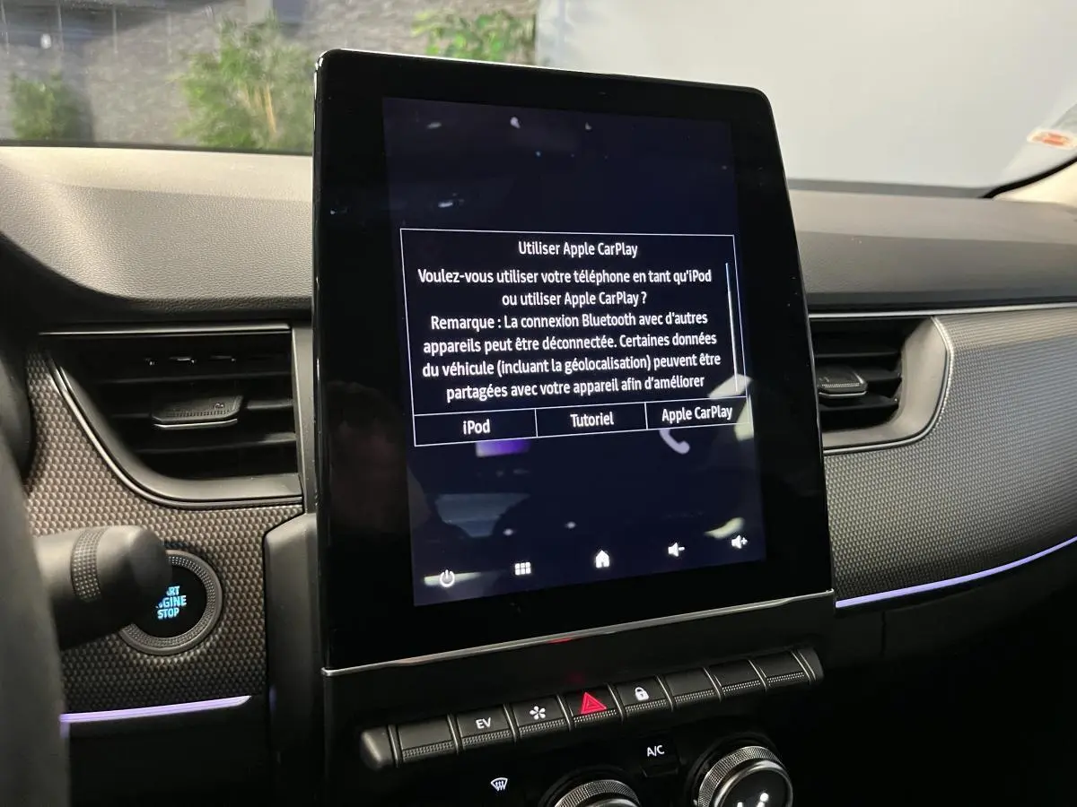 Vue rapprochée de la console centrale noire du Renault Arkana 2021 avec écran tactile affichant Apple CarPlay.