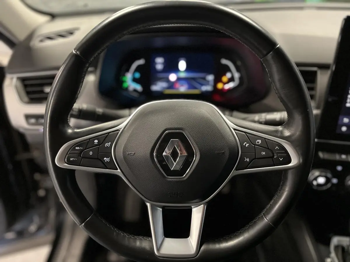 Volant cuir noir de Renault Arkana 2021 vu de face avec commandes intégrées et tableau de bord numérique flou en arrière-plan.