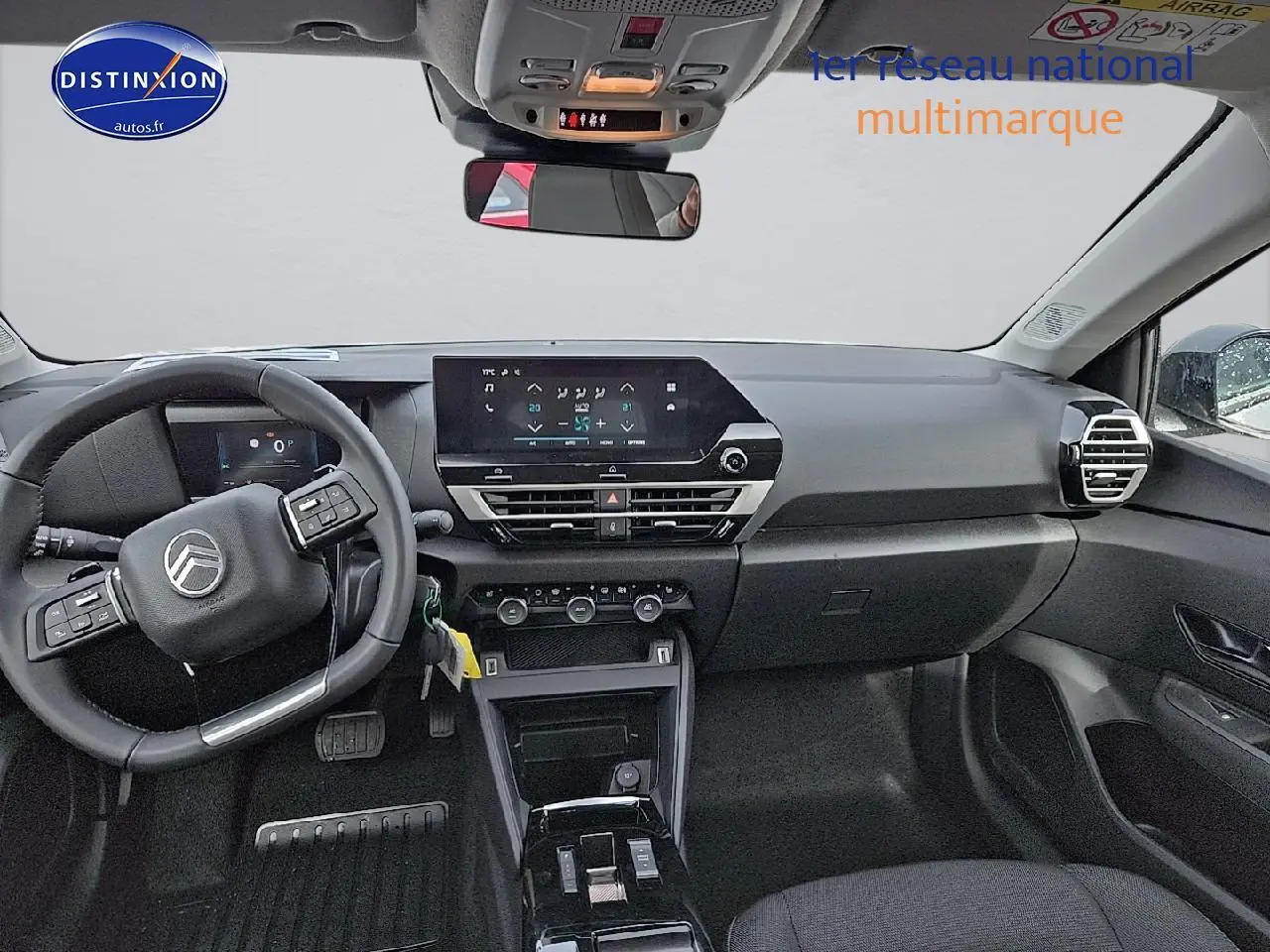 Vue intérieure avant de la Citroën C4 blanche, tableau de bord avec écran tactile et volant multifonction noir.