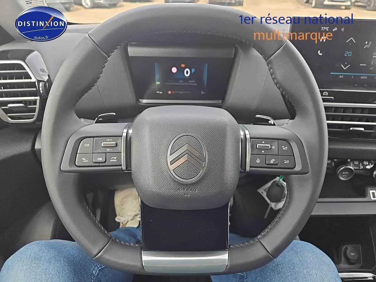 Vue centrée sur le volant cuir noir du Citroën C4 1.2 hybride 145 plus avec tableau de bord numérique en arrière-plan.