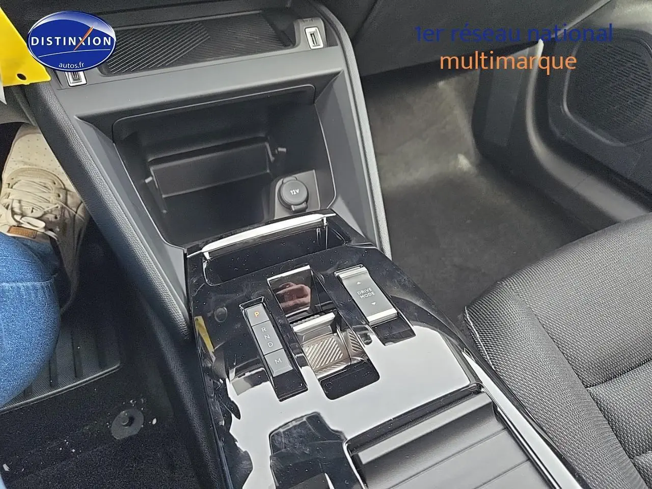 Vue rapprochée de la console centrale noire brillante avec sélecteur de boîte automatique et accoudoir tissu noir dans une Citroën C4 blanche.