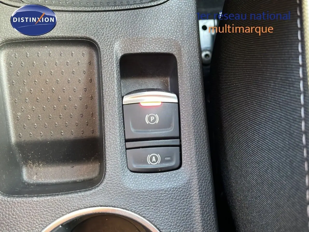 Gros plan sur la console centrale de la Renault Symbioz gris cassiopée, avec les boutons de frein à main et auto-hold visibles.