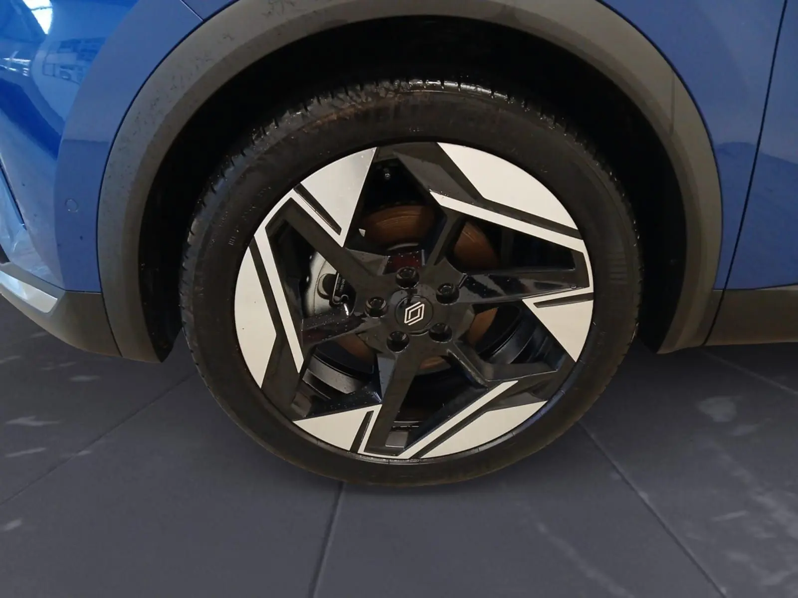 Gros plan sur la roue avant droite du Renault Symbioz 2025 bleu iron, mettant en valeur la jante noire et blanche au design géométrique.