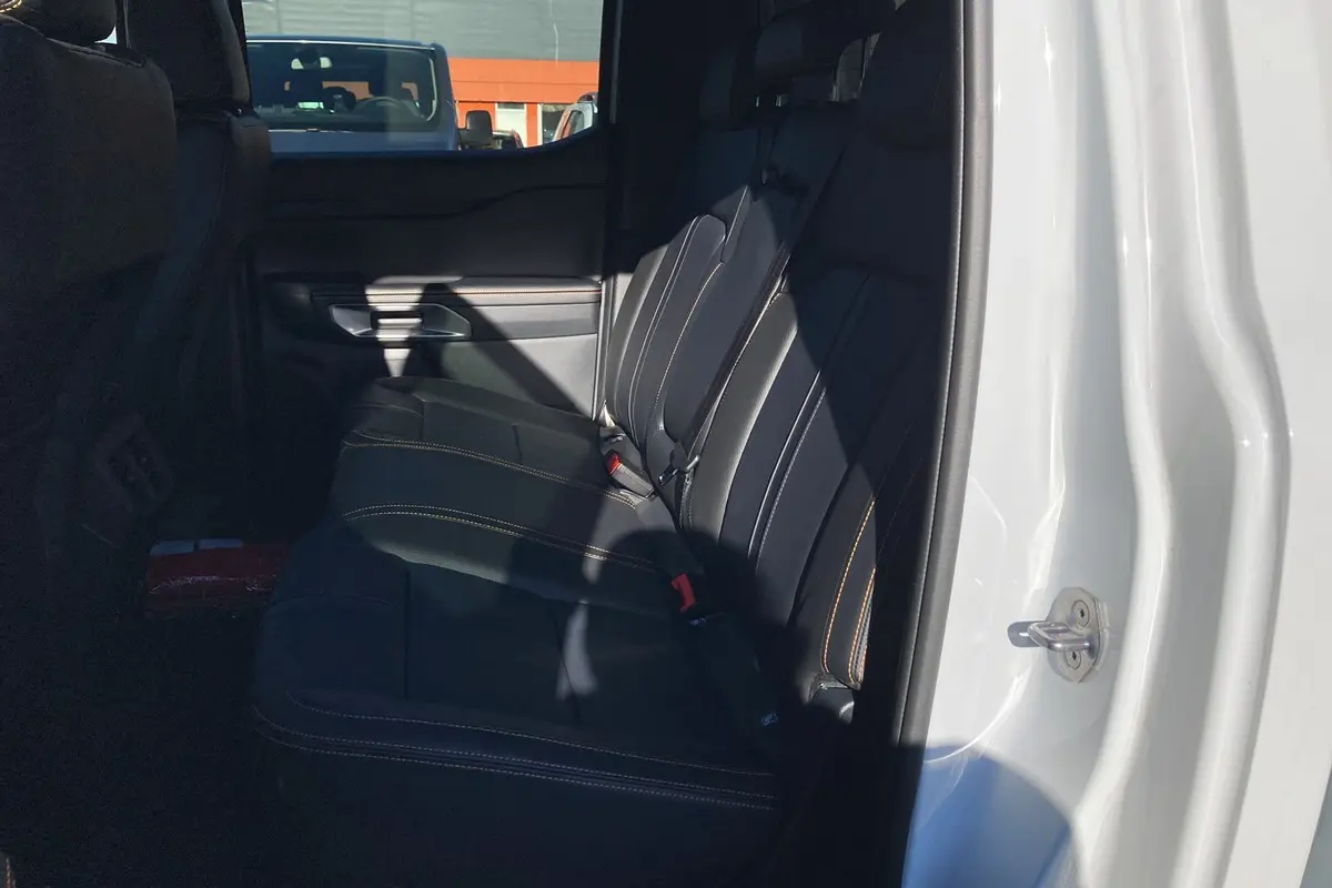 Vue intérieure côté arrière droit du Ford Ranger blanc glacier, montrant les sièges arrière en cuir noir avec surpiqûres contrastantes.