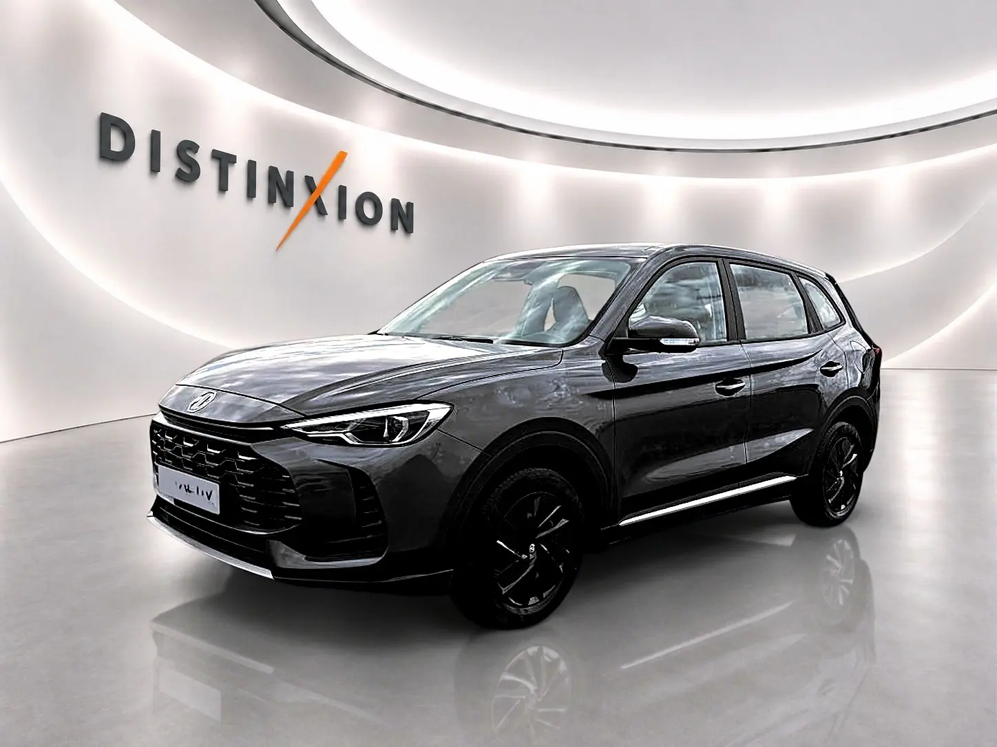 MG Motor ZS 1.5 hybrid 197 Camden grey en 3/4 avant droit, avec calandre noire et jantes sombres dans un showroom lumineux.