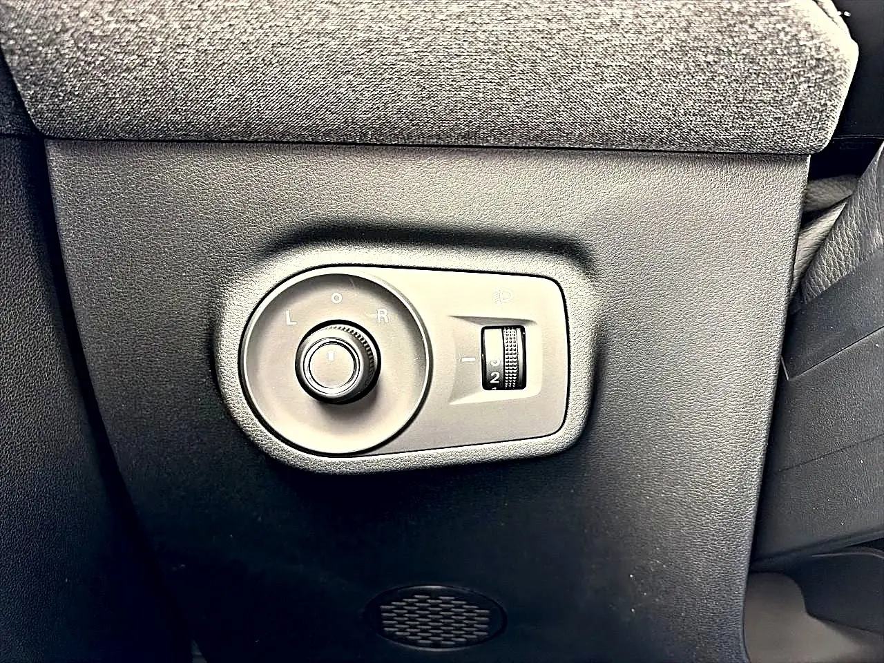 Gros plan sur les commandes de réglage des rétroviseurs et des phares d’un MG Motor ZS 1.5 hybrid gris Camden.