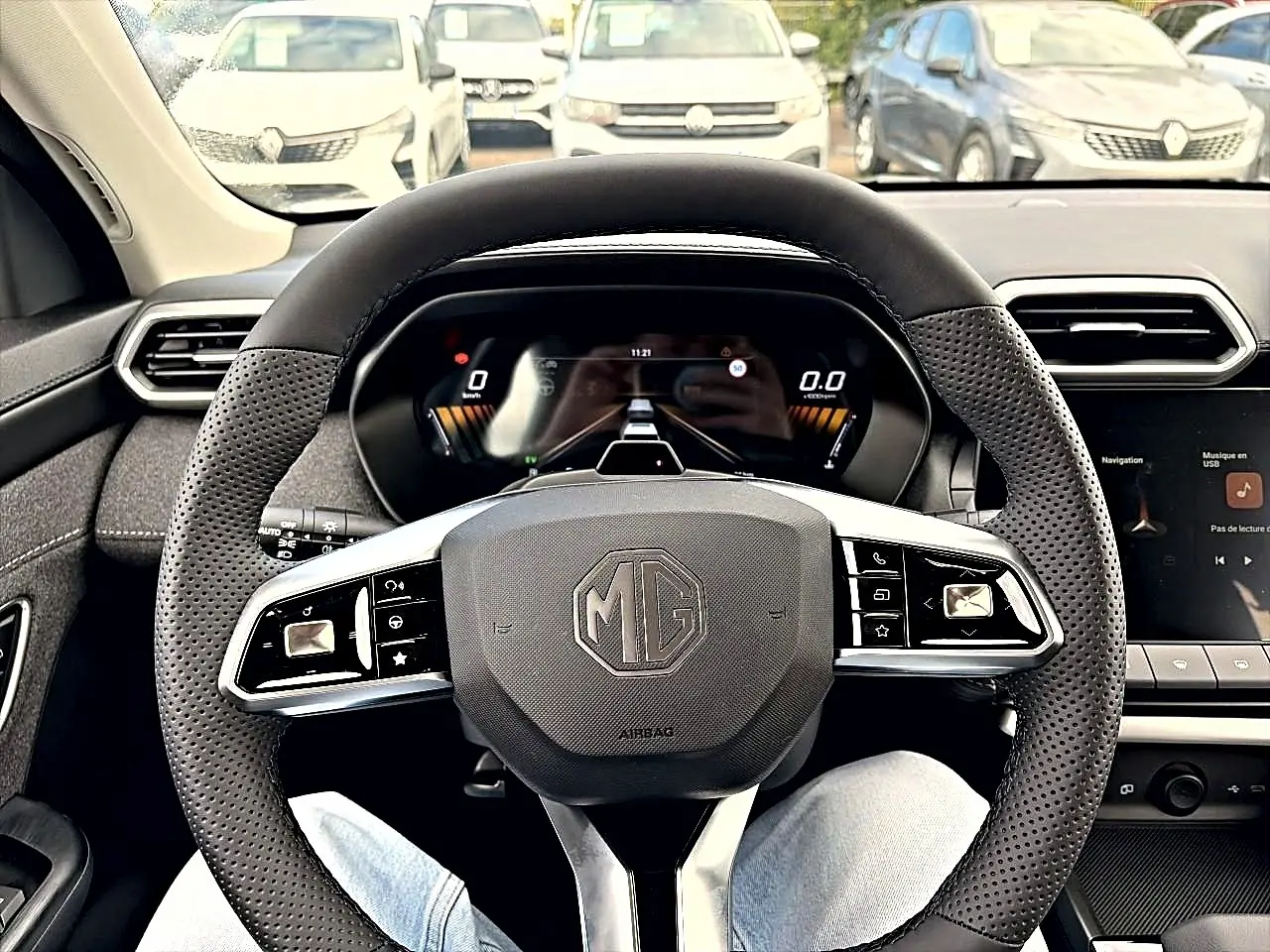 Vue intérieure centrée sur le volant perforé noir du MG ZS 1.5 hybrid 197, avec tableau de bord digital en arrière-plan.