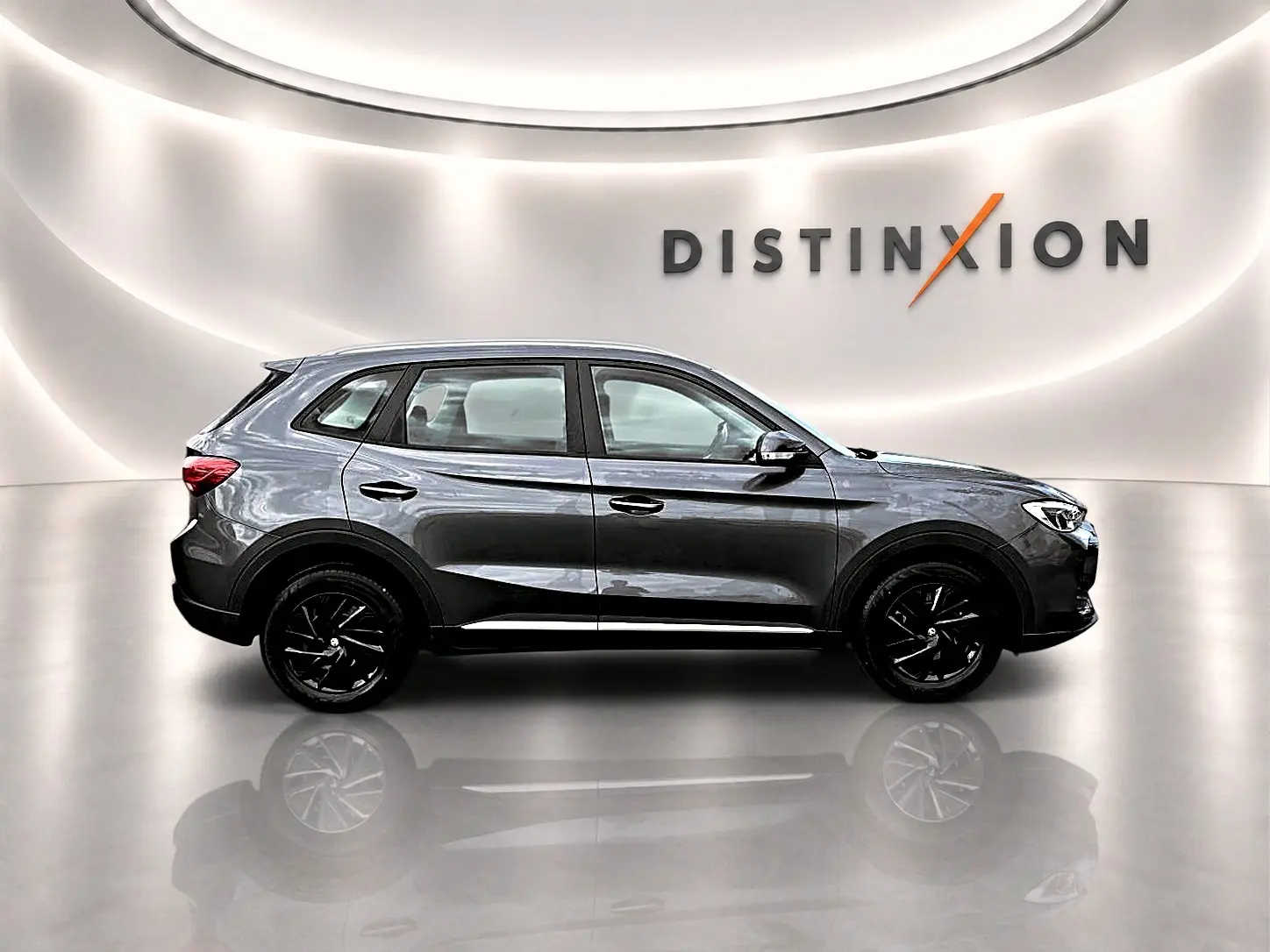 Vue de profil droit du MG ZS 1.5 hybrid 197 Camden grey avec jantes noires dans un showroom lumineux.