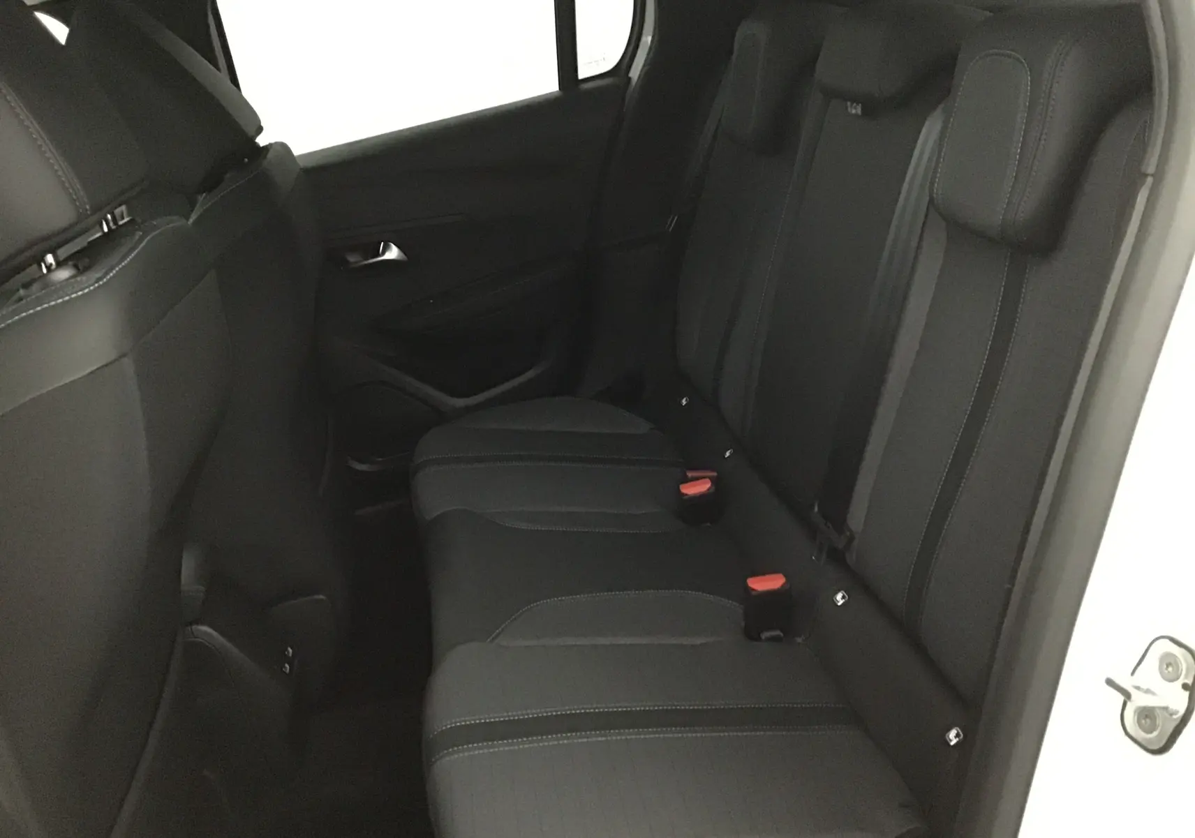 Vue intérieure côté droit des sièges arrière noirs du Peugeot 208 blanc 2024 finition Allure Pack.