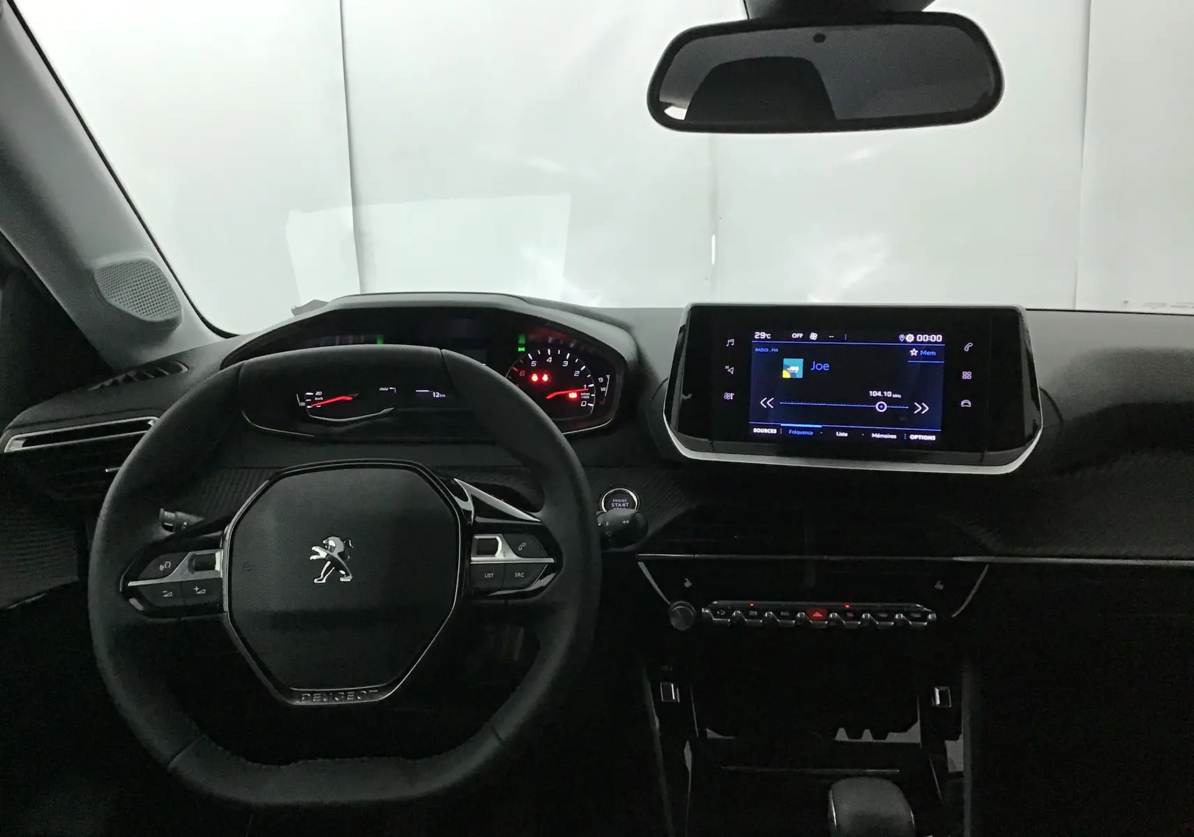 Vue intérieure frontale du tableau de bord de la Peugeot 208 2024 avec écran tactile et volant compact noir.