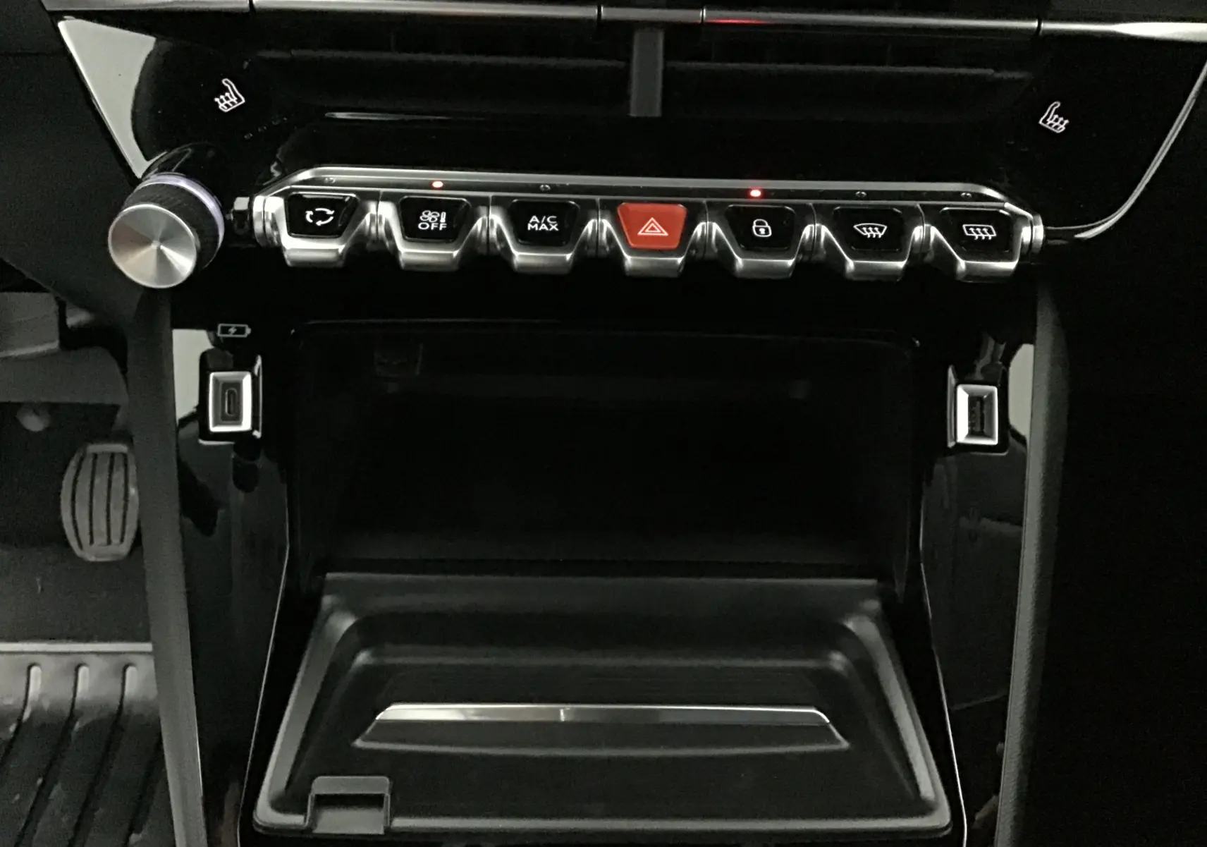 Vue rapprochée de la console centrale noire du Peugeot 208 1.2 PureTech 100 Allure Pack 2024 avec boutons de commande et ports USB.