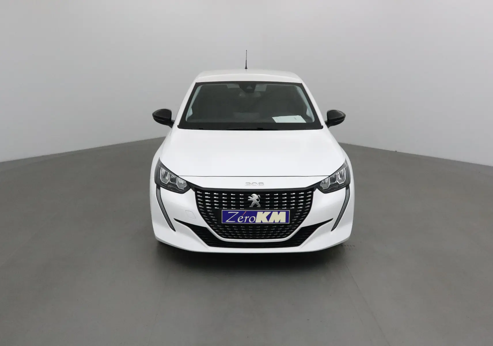 Vue frontale d'une Peugeot 208 blanche 2024 avec calandre noire et logo lion central bien visible.