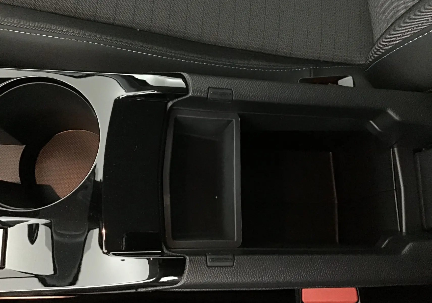 Vue rapprochée de la console centrale noire avec porte-gobelet et rangement du Peugeot 208 blanc 2024.