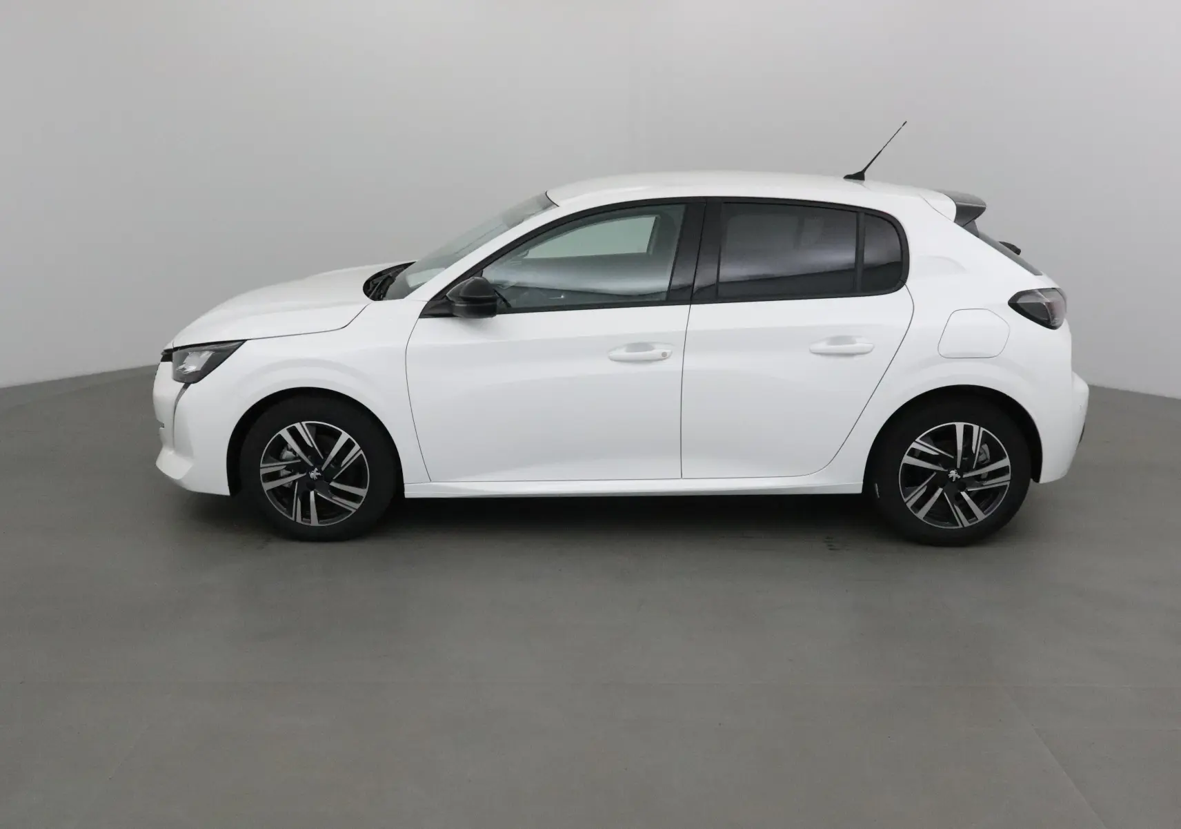 Profil côté gauche d'une Peugeot 208 blanche 2024 avec jantes alliage et vitres teintées sur fond neutre.
