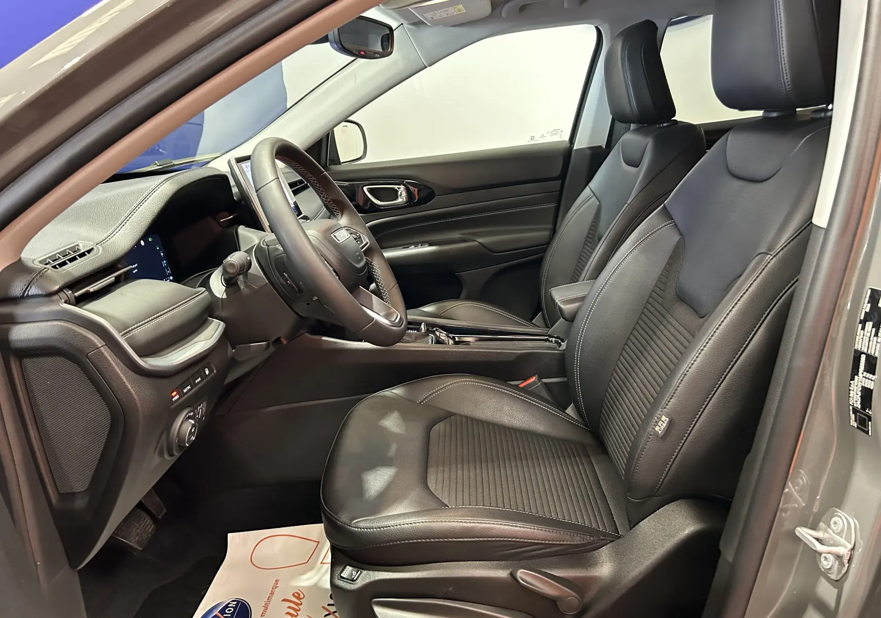 Intérieur avant droit du Jeep Compass gris 2021, sièges cuir noirs et tableau de bord moderne avec écran tactile.