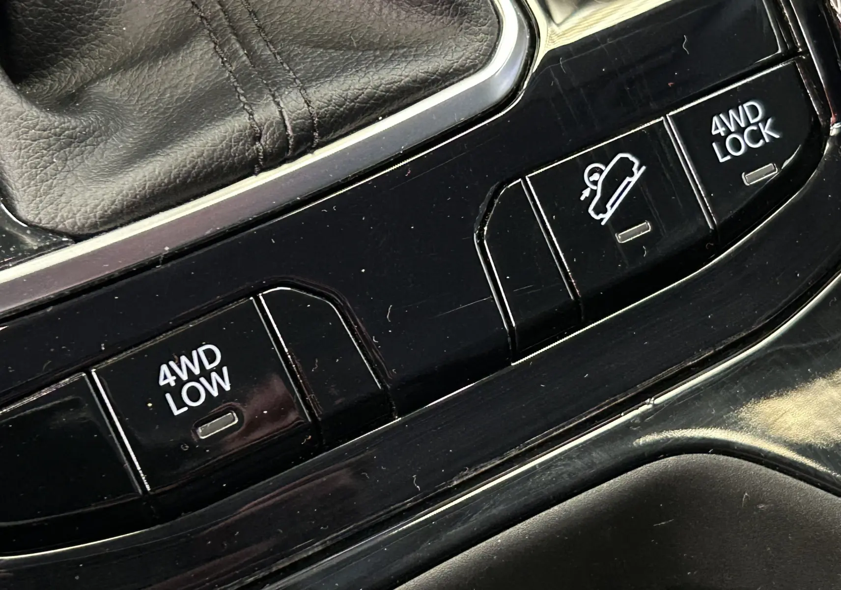 Gros plan sur les boutons de commande 4WD LOW et 4WD LOCK dans l'habitacle noir du Jeep Compass gris.