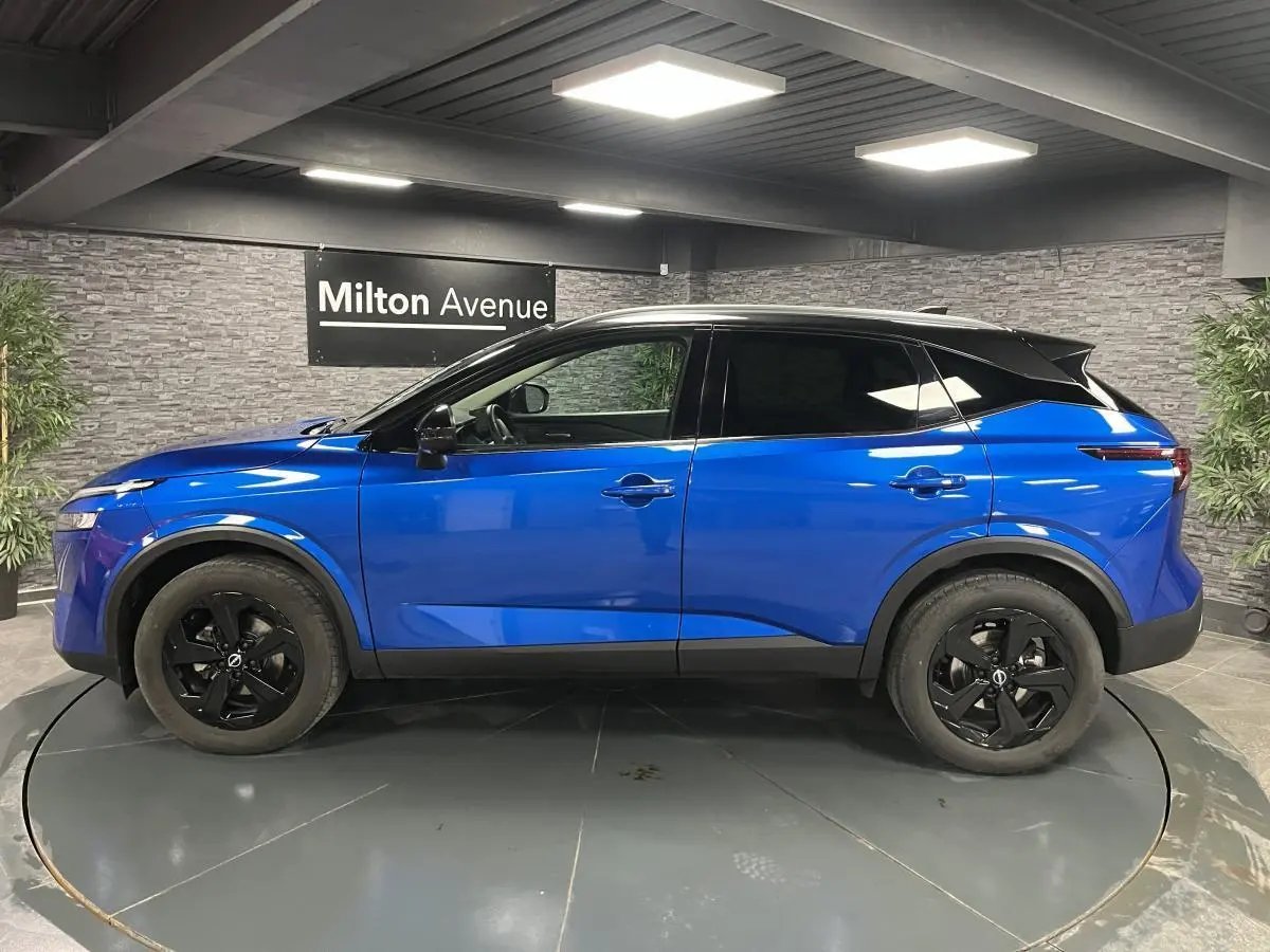 Vue de profil côté gauche d'un Nissan Qashqai 1.3 Mild Hybrid 140 Shadow bleu avec toit noir et jantes noires.