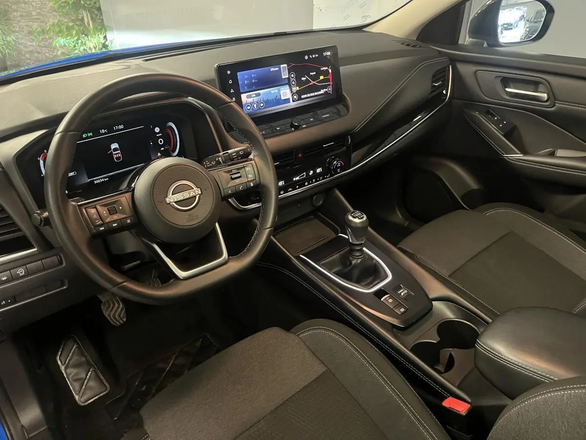 Intérieur avant du Nissan Qashqai 1.3 Mild Hybrid 2024, volant cuir, écran tactile 12,3 pouces et boîte manuelle visible.