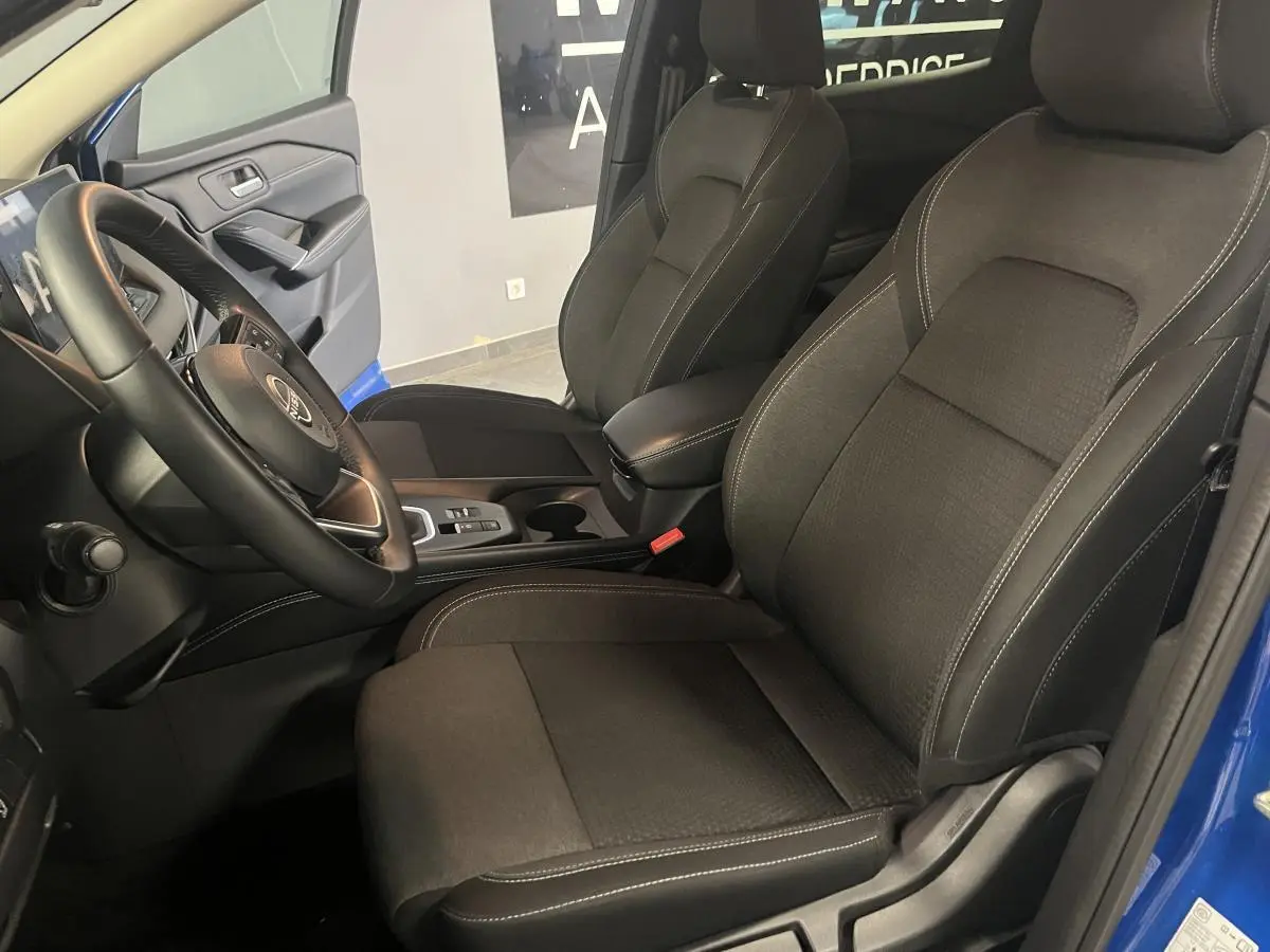 Vue intérieure côté conducteur du Nissan Qashqai 1.3 Mild Hybrid 140 Shadow bleu, sièges tissu noir et console centrale.