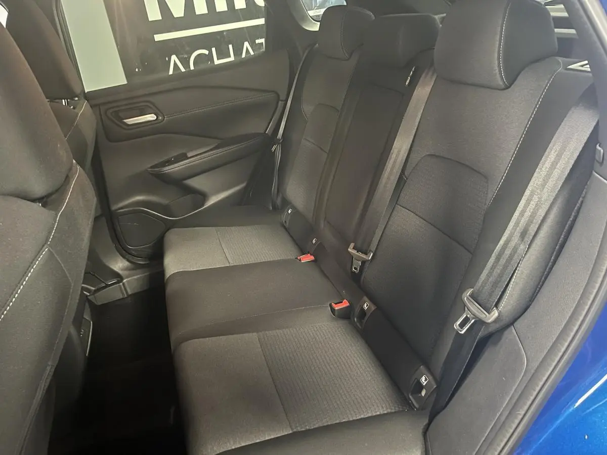 Vue intérieure de la banquette arrière noire du Nissan Qashqai 2024 bleu, avec ceintures et portes ouvertes côté droit.