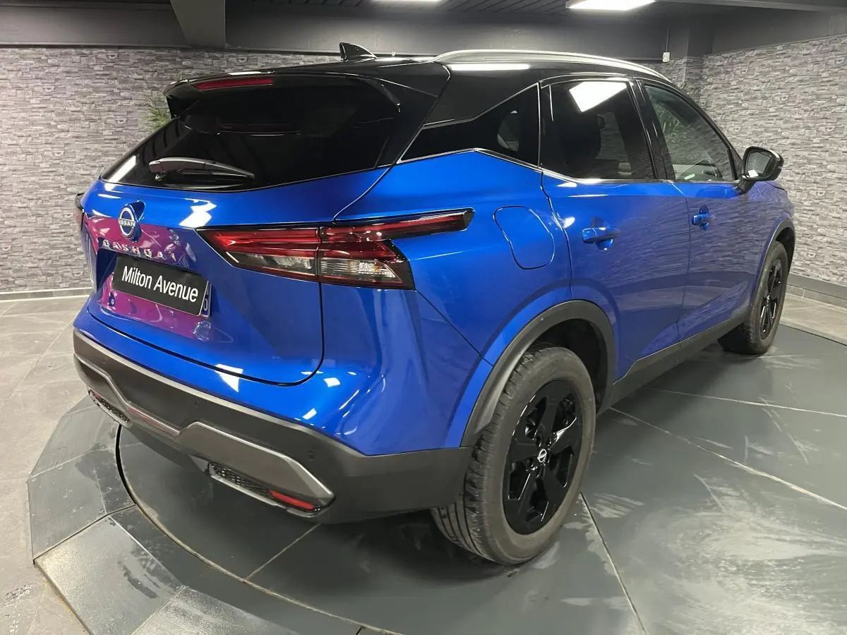 Vue 3/4 arrière droite du Nissan Qashqai 2024 bleu avec toit noir et jantes alliage noires spéciales.