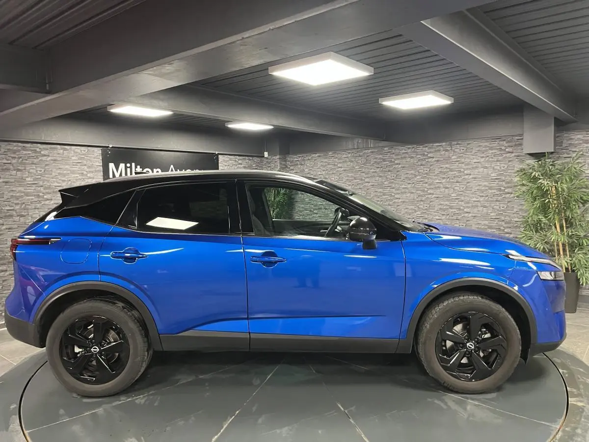 Vue de profil côté gauche d'un Nissan Qashqai 1.3 Mild Hybrid 140 Shadow bleu avec toit noir et jantes noires.