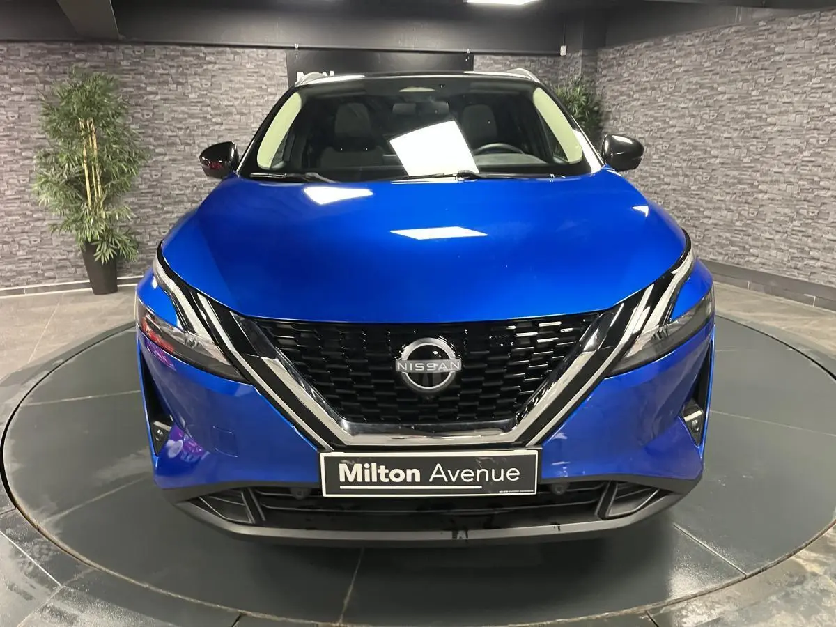 Vue avant d'un Nissan Qashqai 1.3 Mild Hybrid 140 Shadow bleu avec calandre noire et détails chromés.