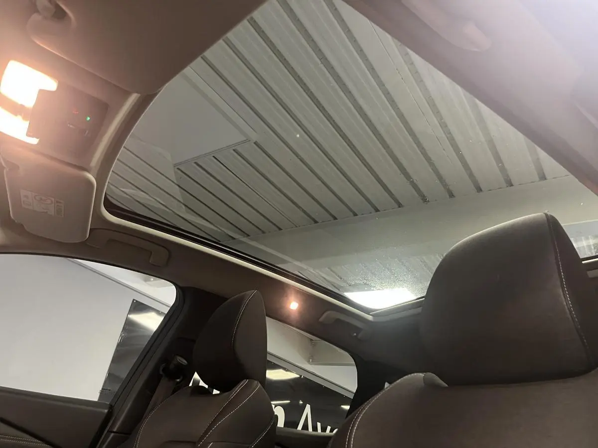 Vue intérieure du toit panoramique en verre et des sièges avant en tissu gris du Nissan Qashqai 2024.