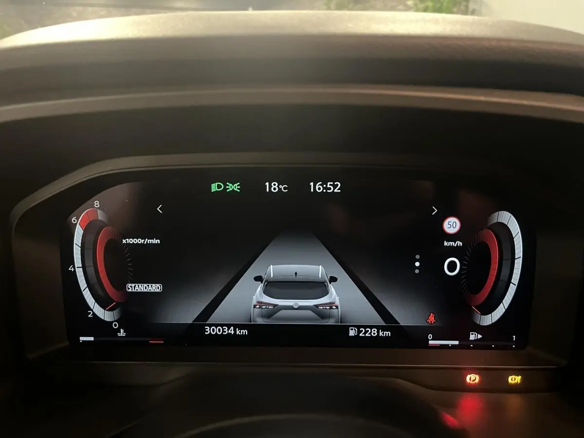 Affichage numérique du tableau de bord du Nissan Qashqai 2024 montrant une vue arrière stylisée du véhicule en gris.