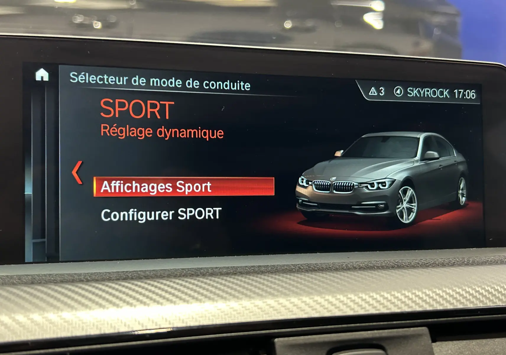 Écran de la BMW Série 3 320i blanc montrant le mode de conduite Sport avec vue 3/4 avant du véhicule en illustration.