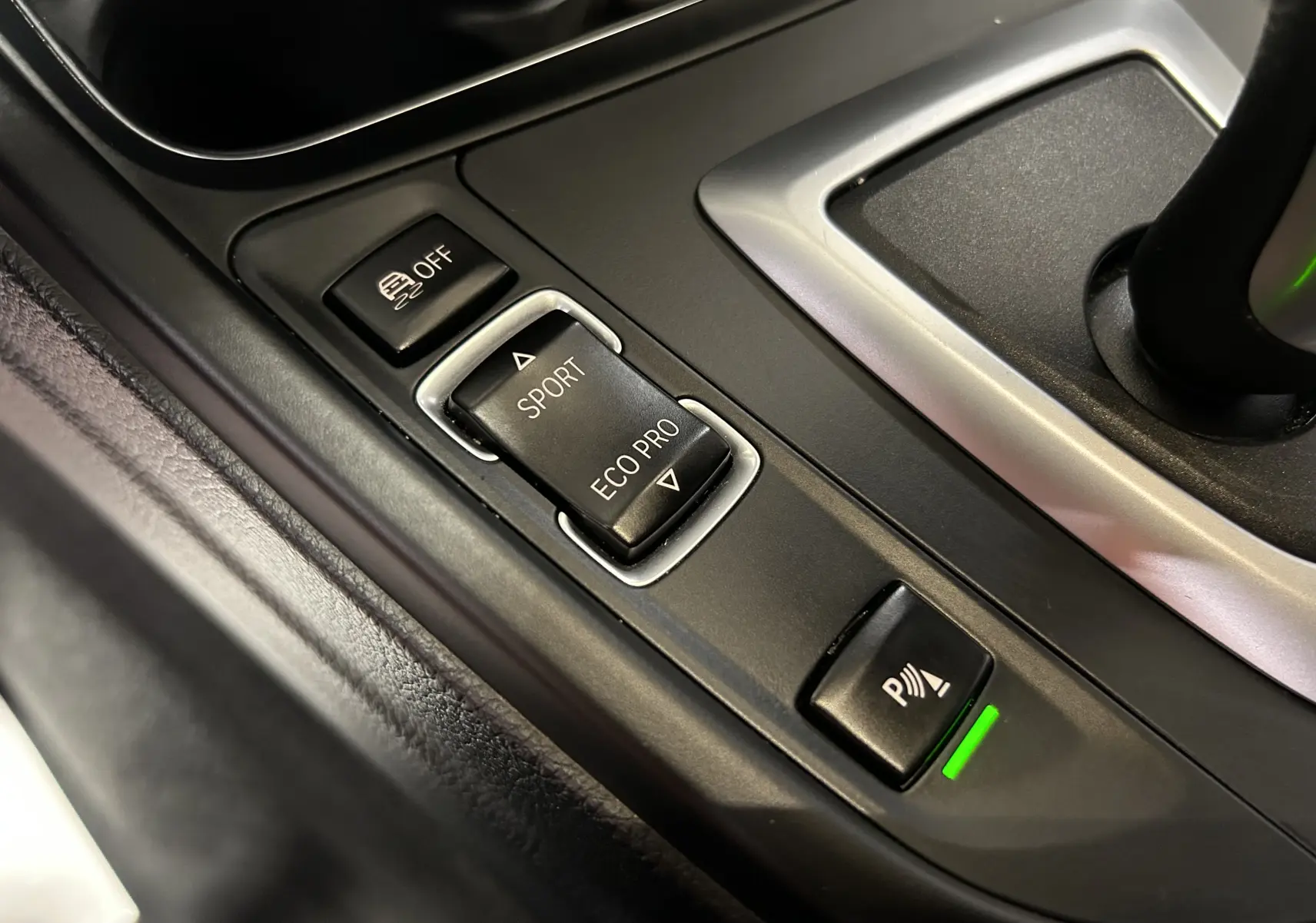 Gros plan sur la console centrale noire de la BMW Série 3 320i 2018, avec boutons mode Sport et Eco Pro visibles.