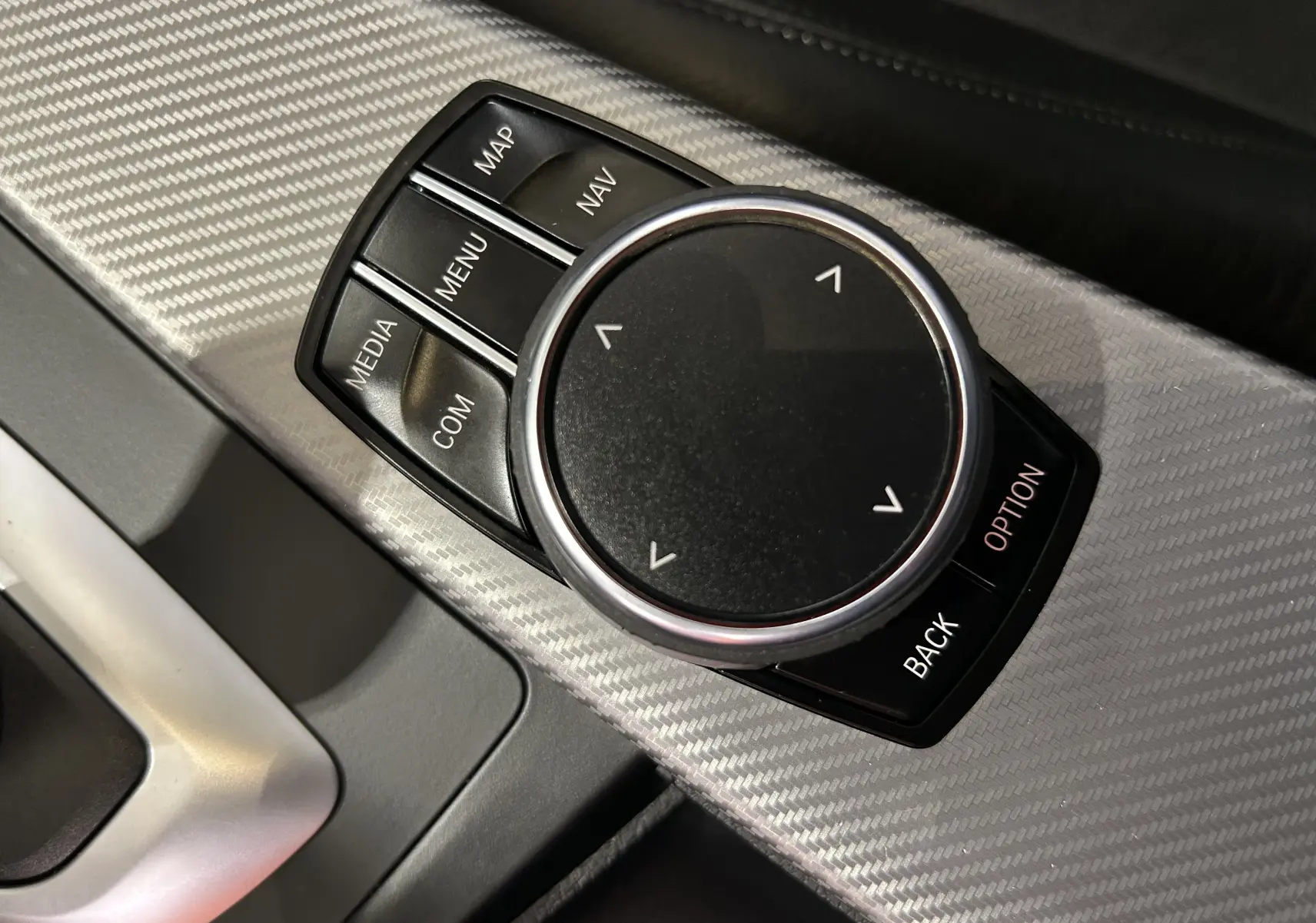 Gros plan sur la molette de commande du système GPS dans l'habitacle d'une BMW Série 3 blanche de 2018.