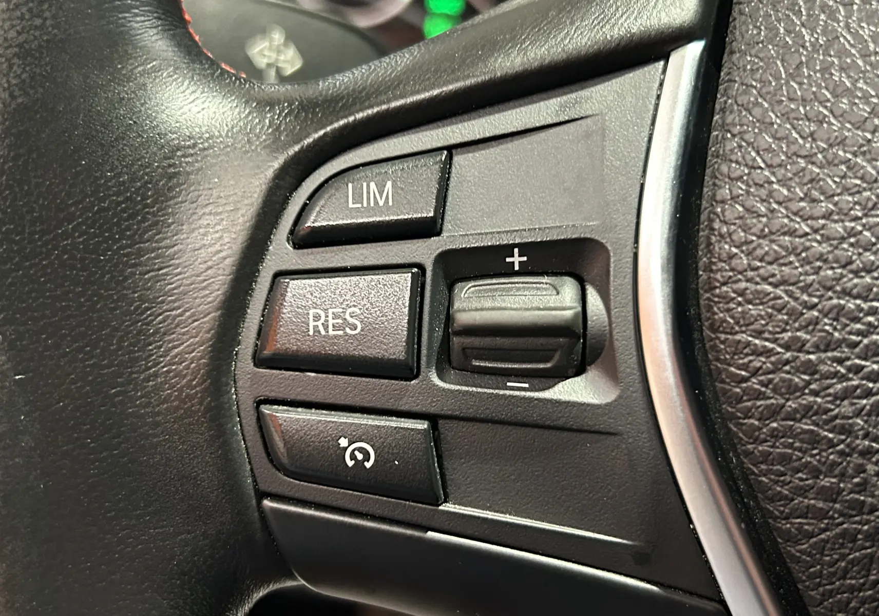 Gros plan sur les commandes de régulateur de vitesse au volant cuir noir d'une BMW Série 3 320i blanche de 2018.