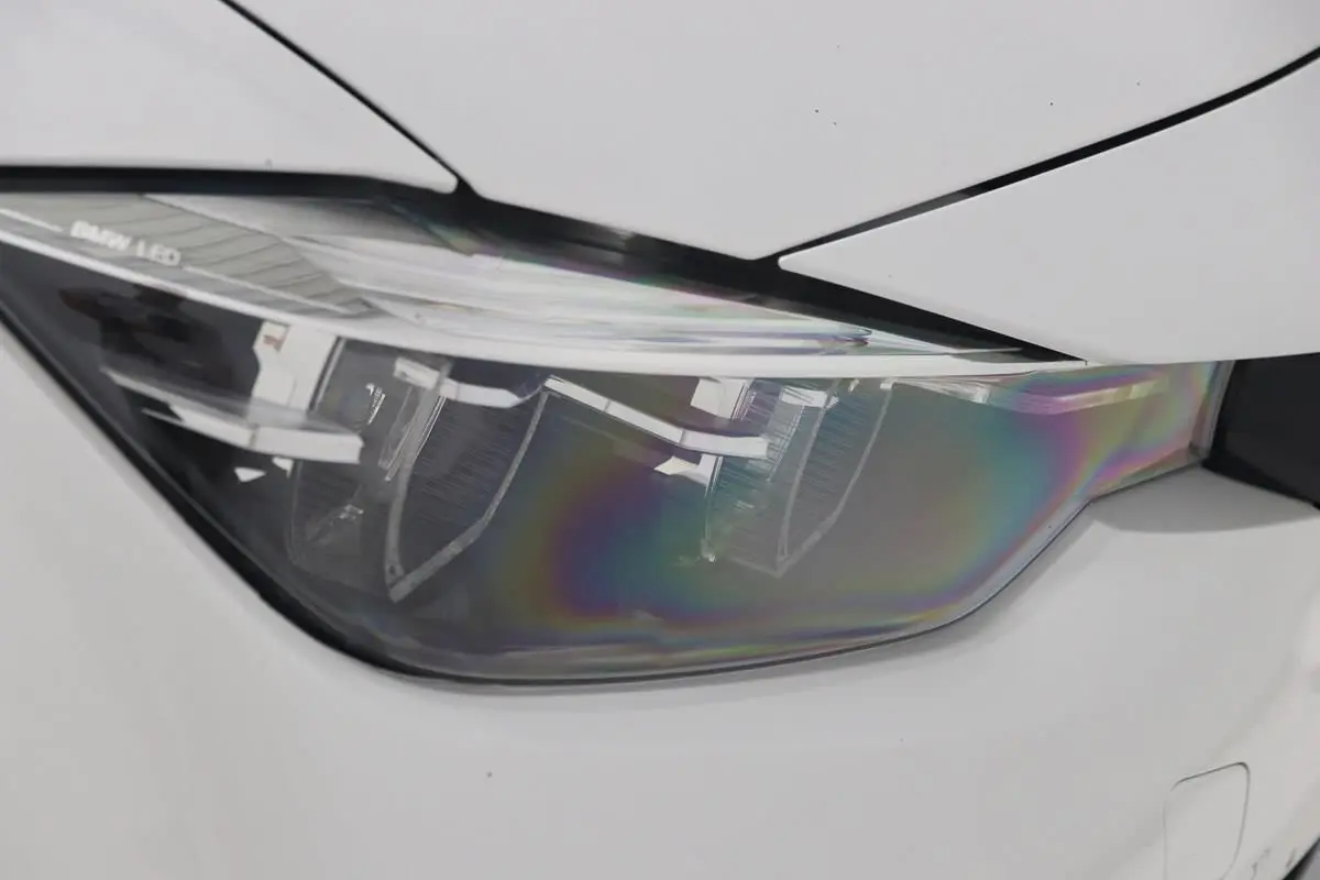 Gros plan sur le phare avant gauche LED d'une BMW Série 3 320i blanche de 2018 avec carrosserie lisse.