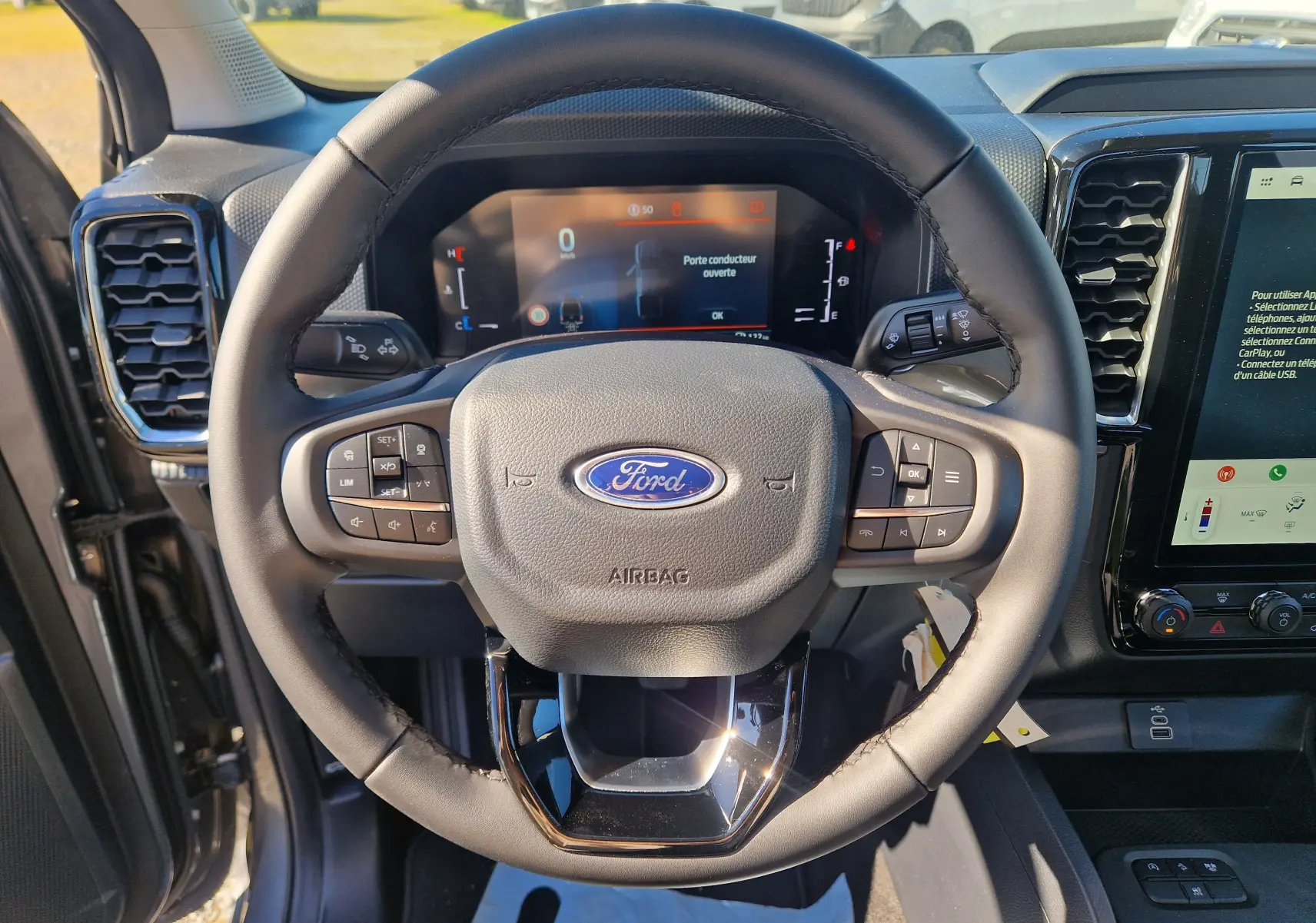 Vue rapprochée du volant noir du Ford Ranger Super Cabine 2026, avec tableau de bord digital et commandes intégrées.