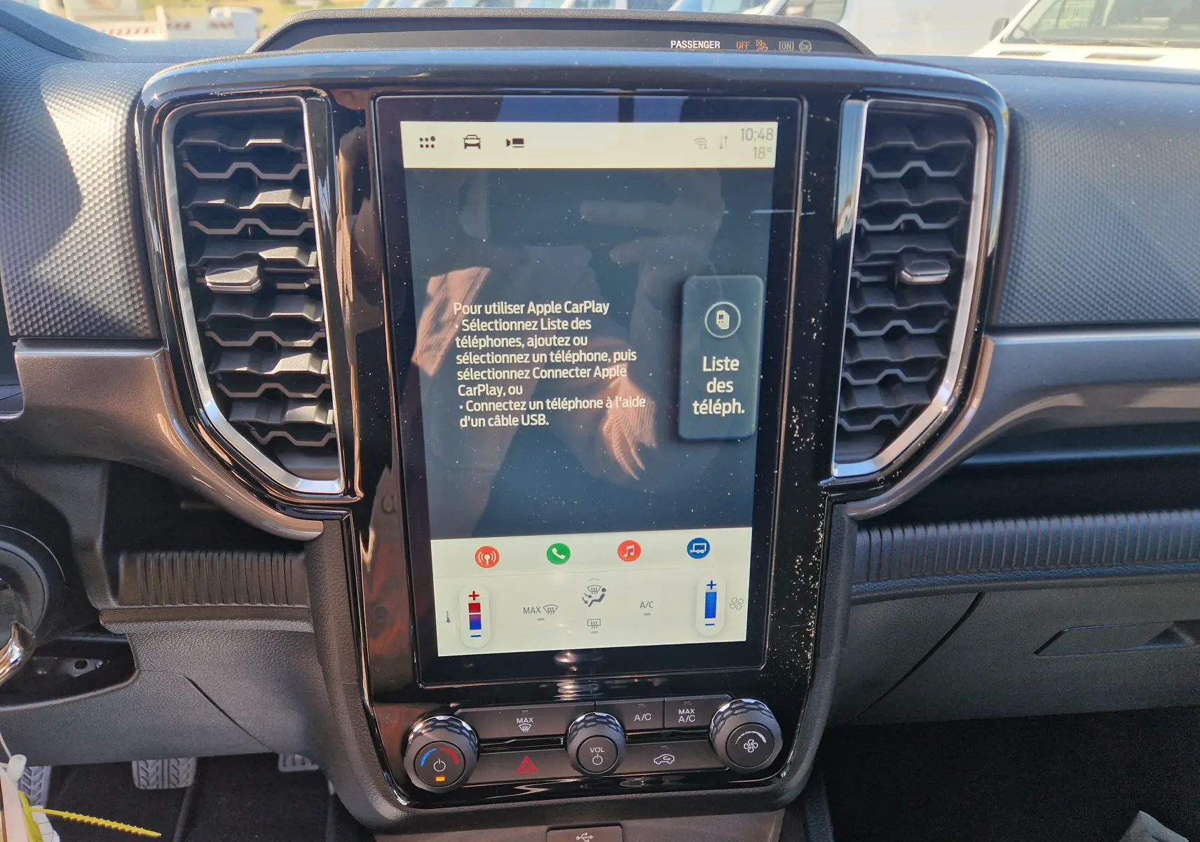 Vue rapprochée de l’écran tactile central noir brillant du Ford Ranger Super Cabine gris carbone, avec commandes climatisation visibles.