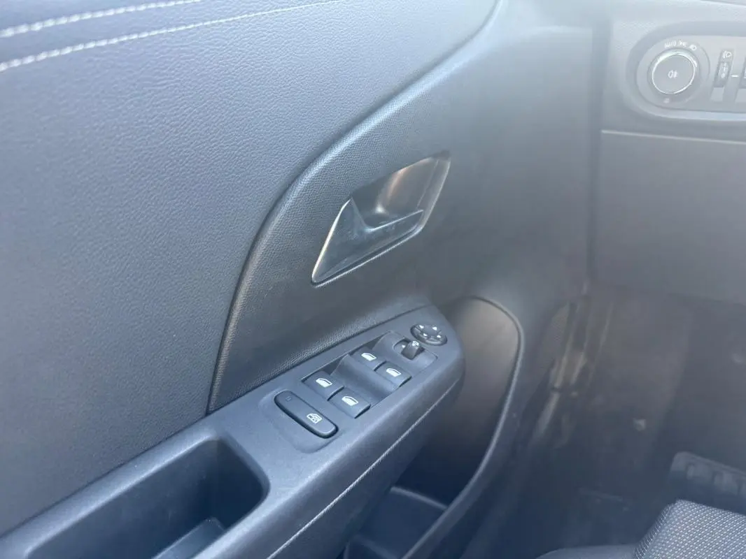 Vue rapprochée de la porte avant gauche intérieure de l’Opel Corsa rouge, avec commandes des vitres électriques et poignée noire.