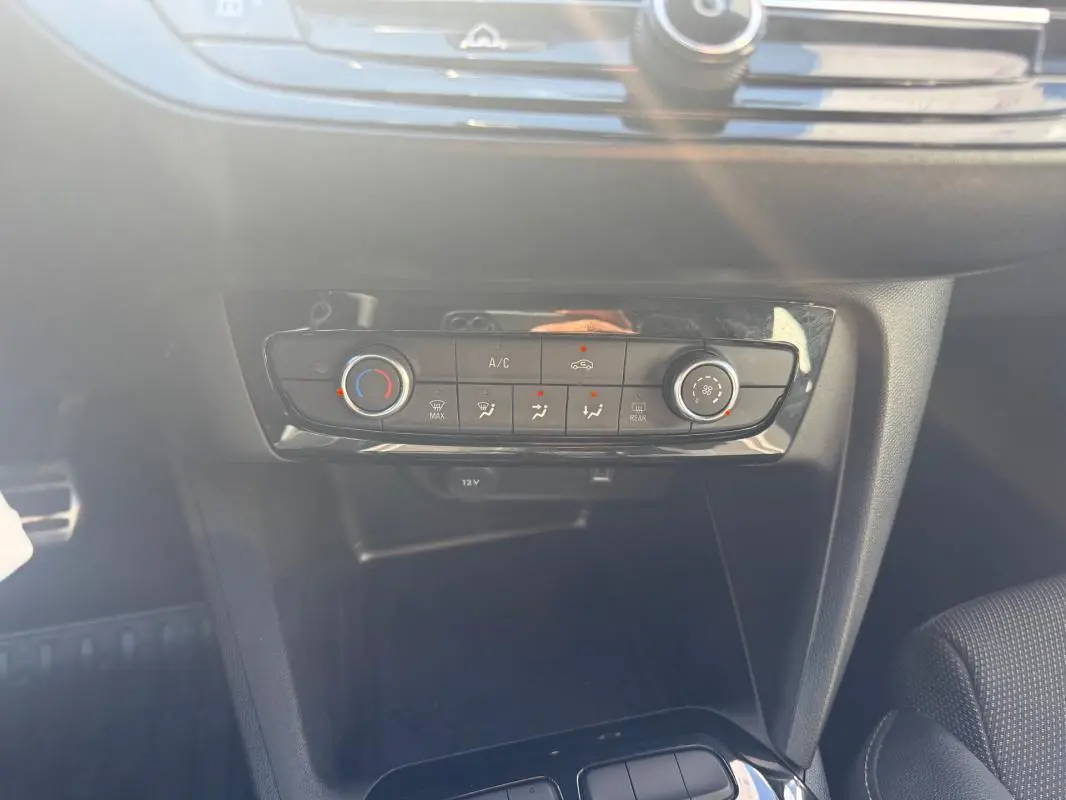 Gros plan sur la console centrale de l’Opel Corsa rouge 2025, mettant en valeur les commandes de climatisation manuelle.