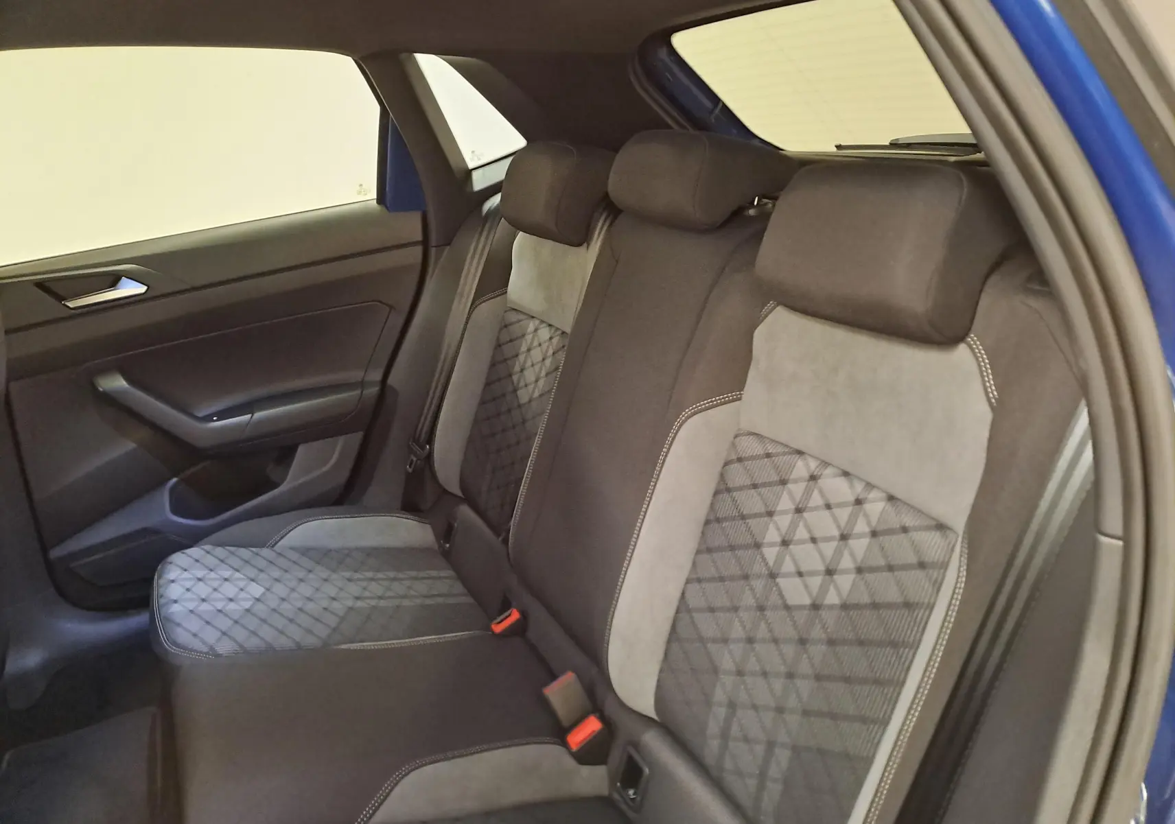 Vue intérieure côté arrière droit du Volkswagen Polo 2025 Bleu Récif, sièges arrière en tissu et alcantara gris avec surpiqûres.