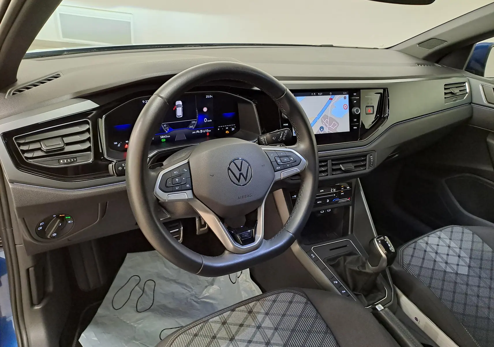 Vue intérieure du poste de conduite de la Volkswagen Polo 2025, volant multifonction et écran tactile avec navigation visible.