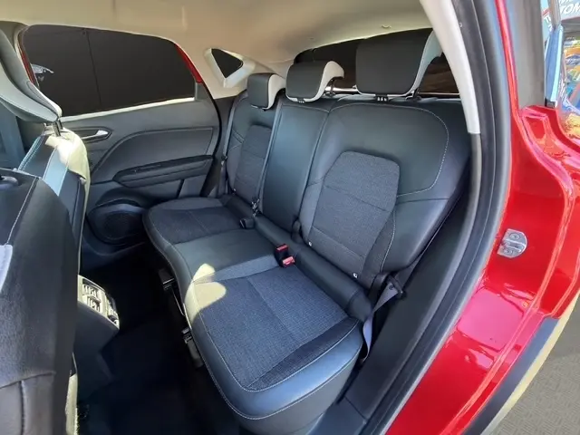 Vue intérieure côté droit des sièges arrière noirs et gris du Renault Captur rouge 2024, avec appuie-têtes et ceintures visibles.