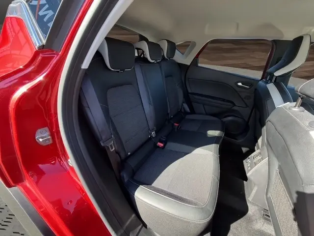 Vue intérieure sur la banquette arrière du Renault Captur rouge 2024, montrant les sièges en tissu et les ceintures de sécurité.