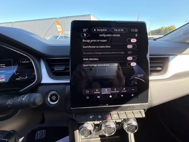 Vue rapprochée de la console centrale tactile du Renault Captur rouge 2024, affichant les réglages de verrouillage et navigation.
