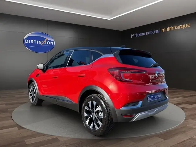 Renault Captur Techno TCe 90 rouge vu en 3/4 arrière droit, toit noir et jantes alliage distinctives.