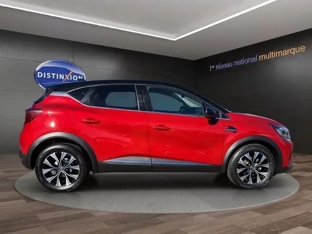 Vue latérale droite d'un Renault Captur rouge 2024 avec toit noir, jantes alliage et détails noirs contrastants.