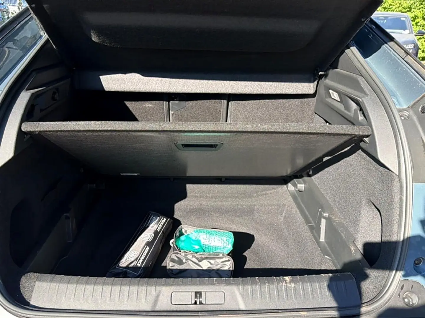 Coffre ouvert vu de l'arrière d'un Peugeot 3008 bleu Ingara avec plancher mobile et accessoires de sécurité.