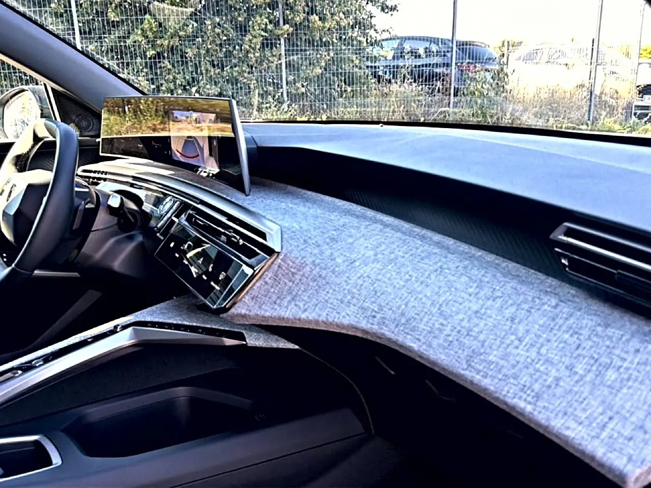 Vue intérieure côté passager du tableau de bord du Peugeot 3008 2025 avec écran tactile et finition tissu gris clair.