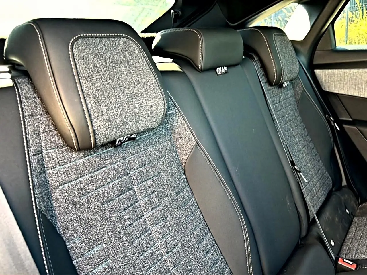 Vue rapprochée de la banquette arrière du Peugeot 3008 2025, tissu gris avec appuis-tête cuir noir et surpiqûres contrastées.