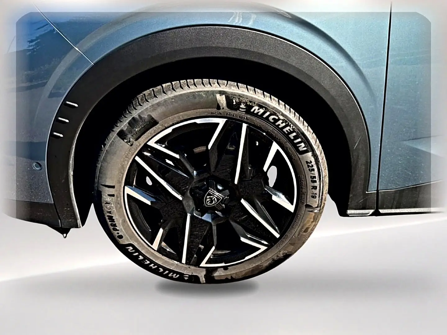 Gros plan sur la roue arrière droite bleu ingaro d’un Peugeot 3008 1.2 hybrid 145 allure e-dcs6 avec jante alu noire et argent.